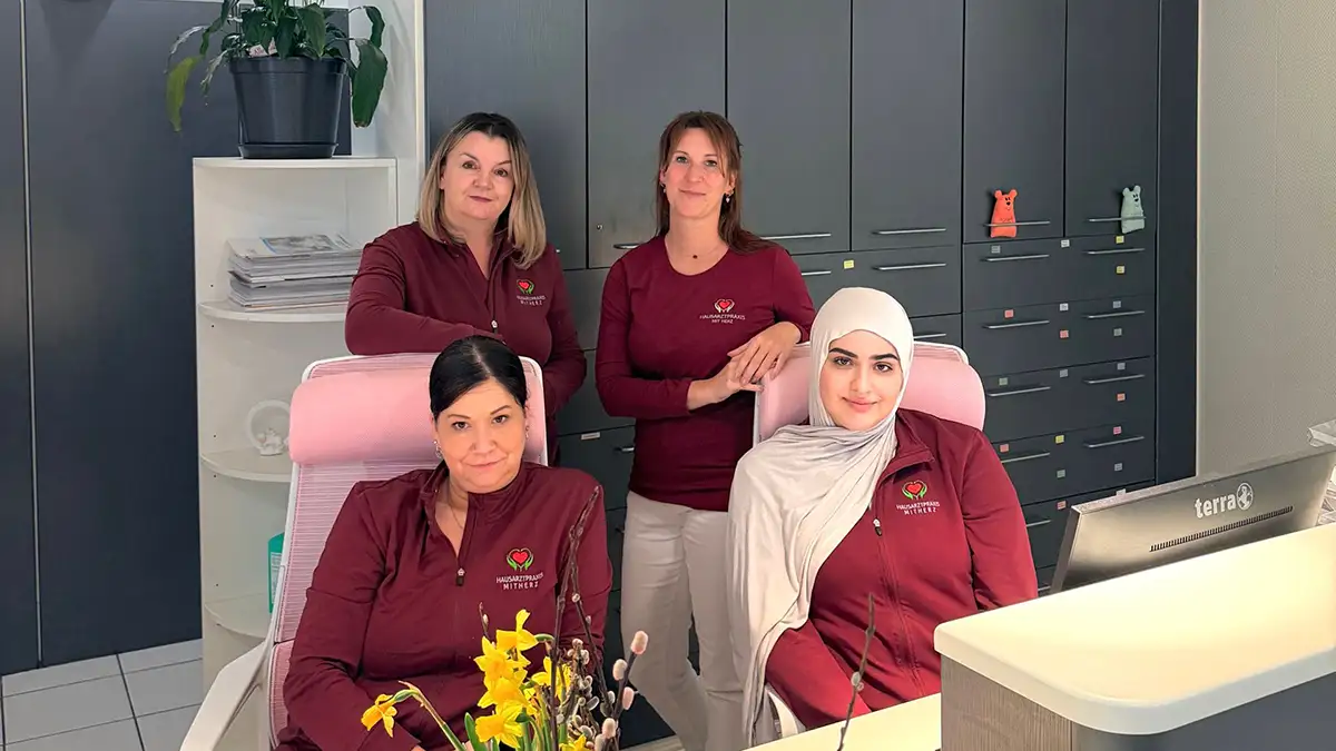 Vielfältiges medizinisches Team steht lächelnd zusammen in der Ordination